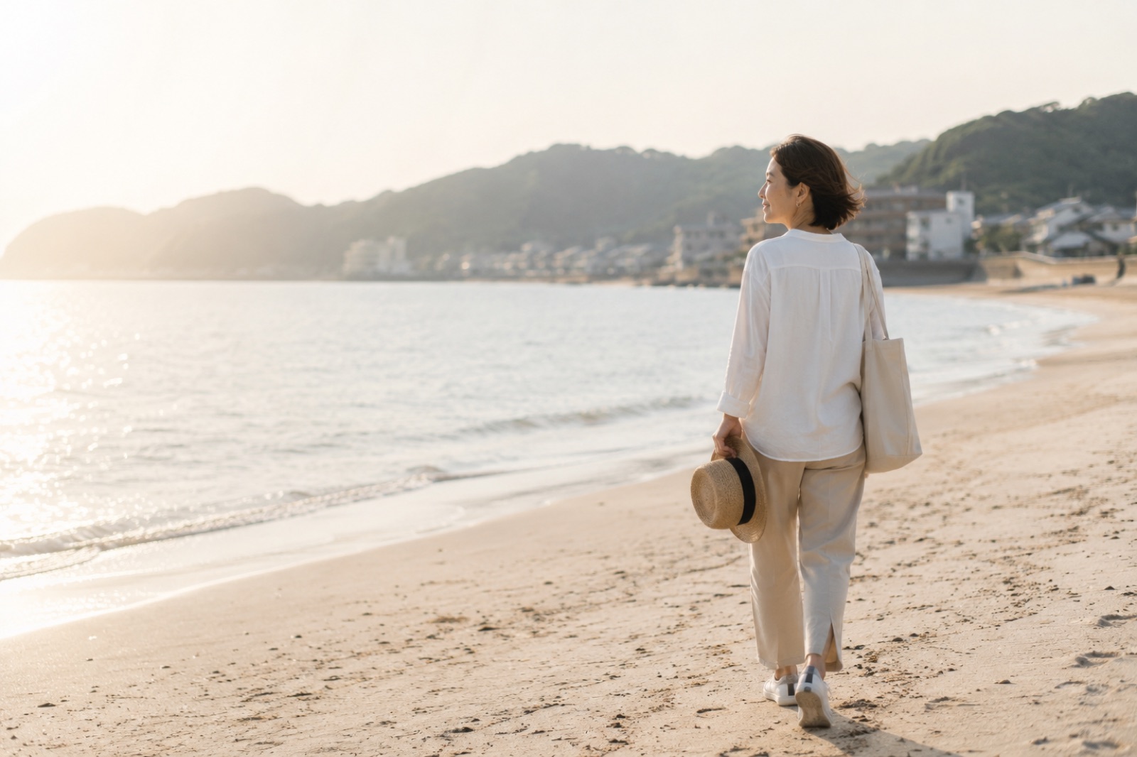 夕暮れの海辺を、自分のペースで歩く女性